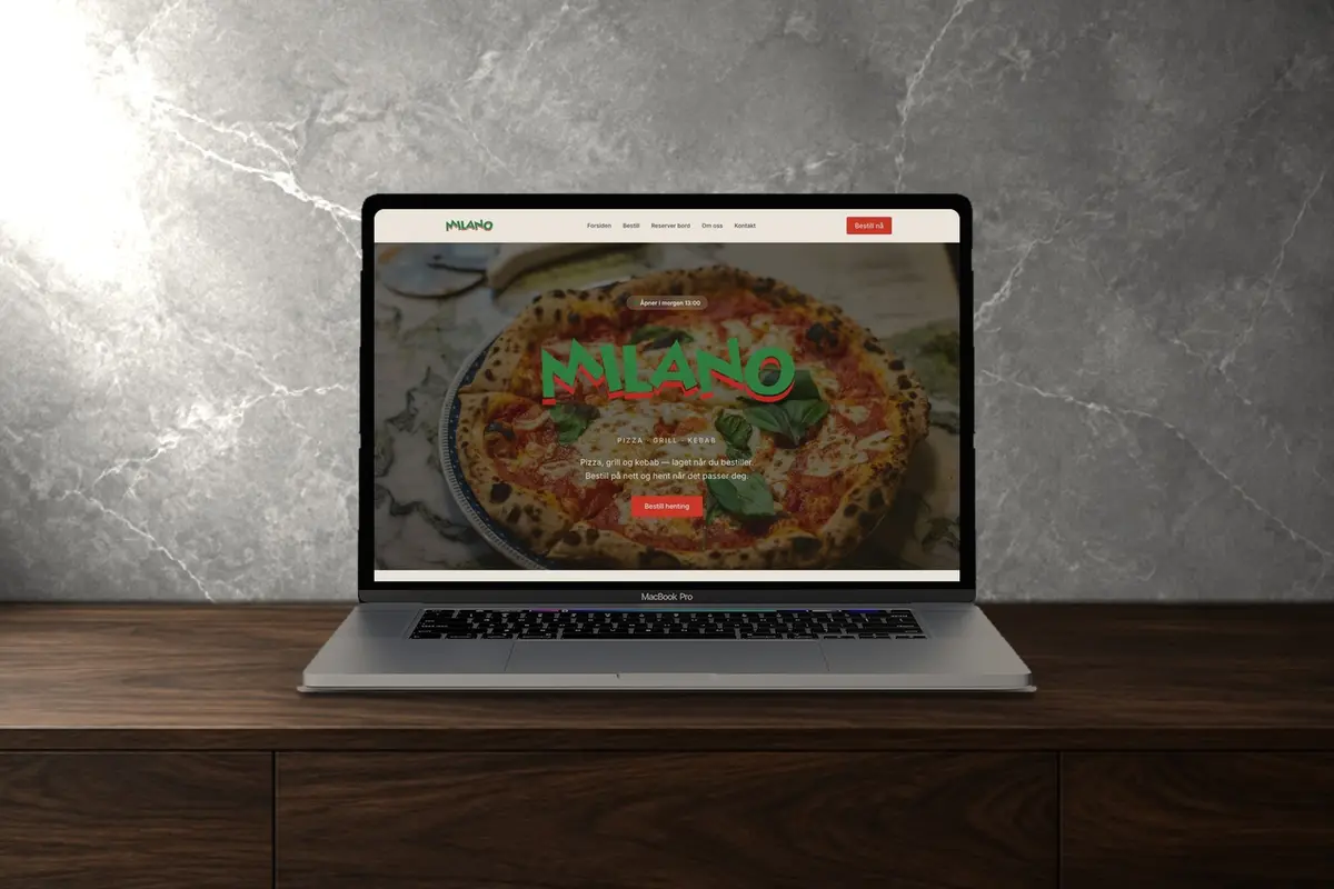 En laptop på en mørk trebenk som viser nettsiden til Milano