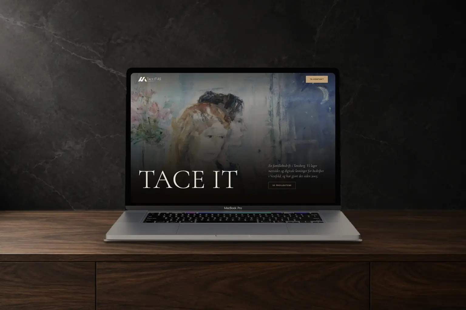 En laptop på en mørk trebenk som viser forsiden til Tace IT